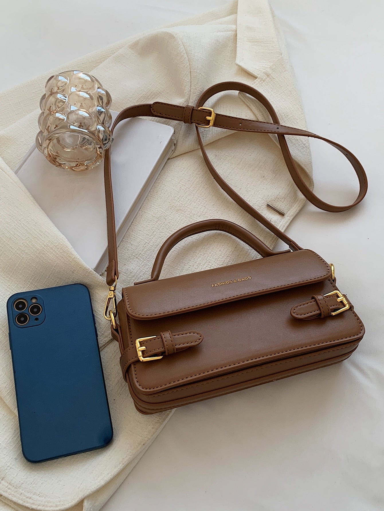 BOLSO CUADRADO CON SOLAPA DECORATIVA Y HEBILLA CON LETRAS EN RELIEVE